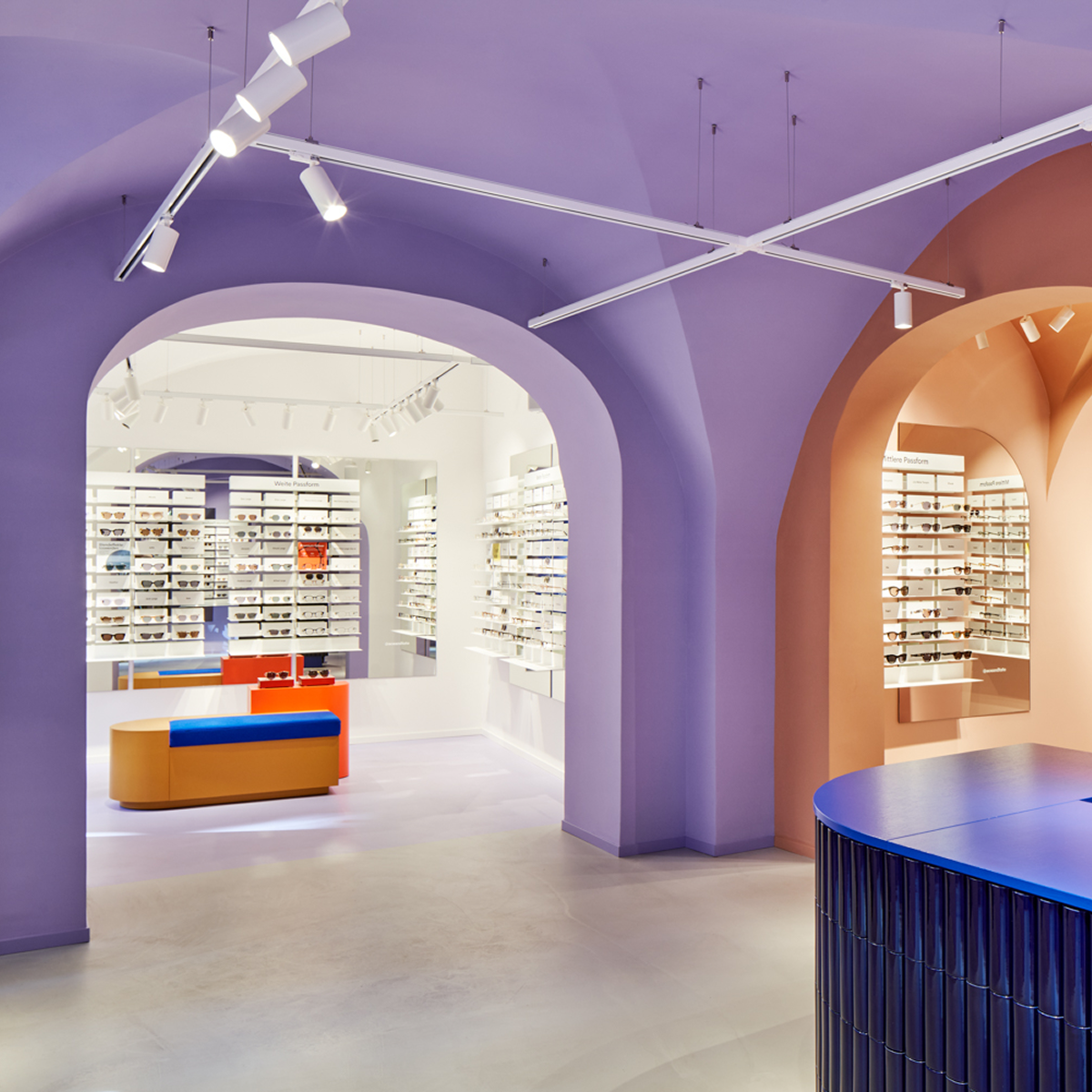 The brightly lit interior of an Ace & Tate optical store, displaying rows of eyeglasses.