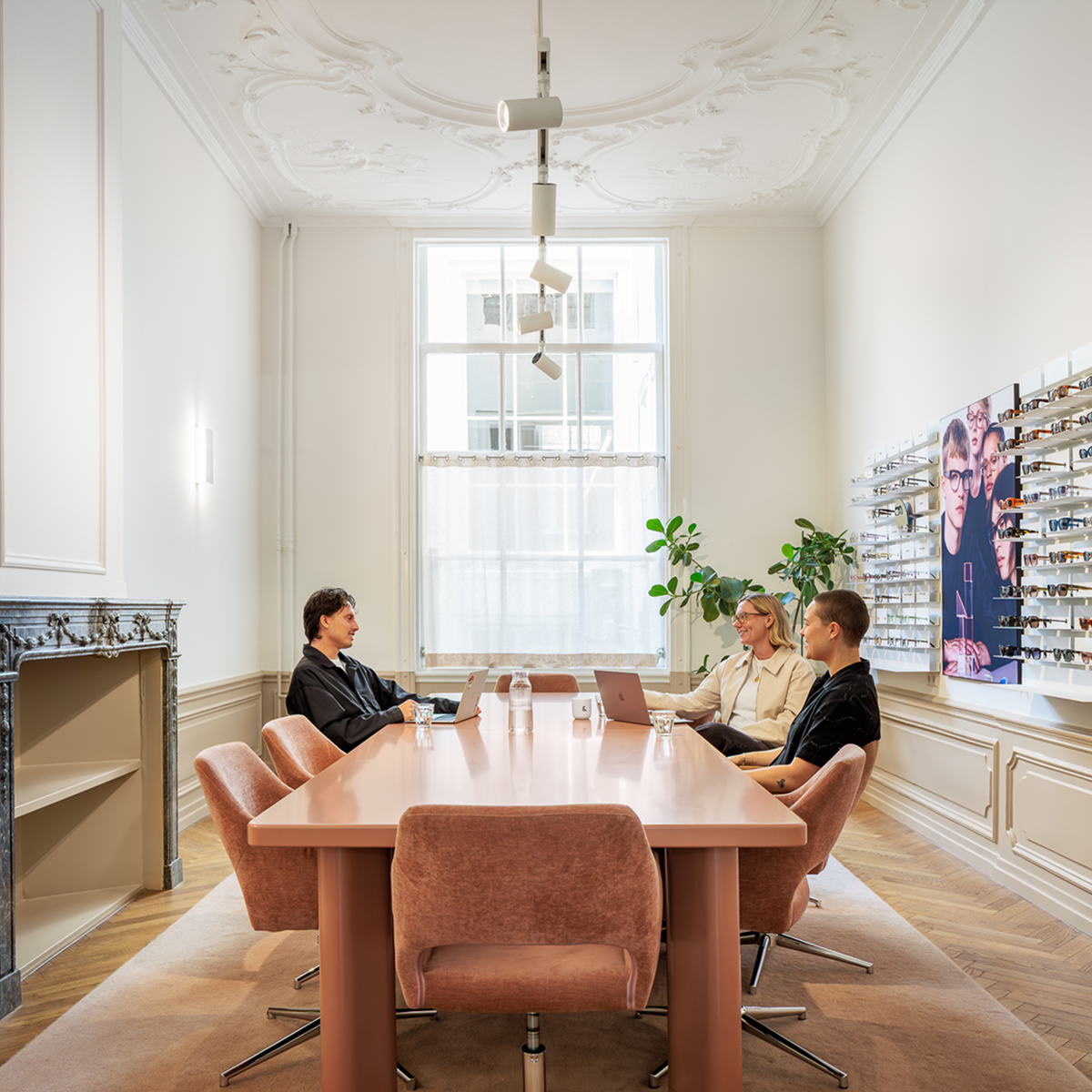 Three Ace & Tate team members collaborating around a large table in a headquarter meeting room.