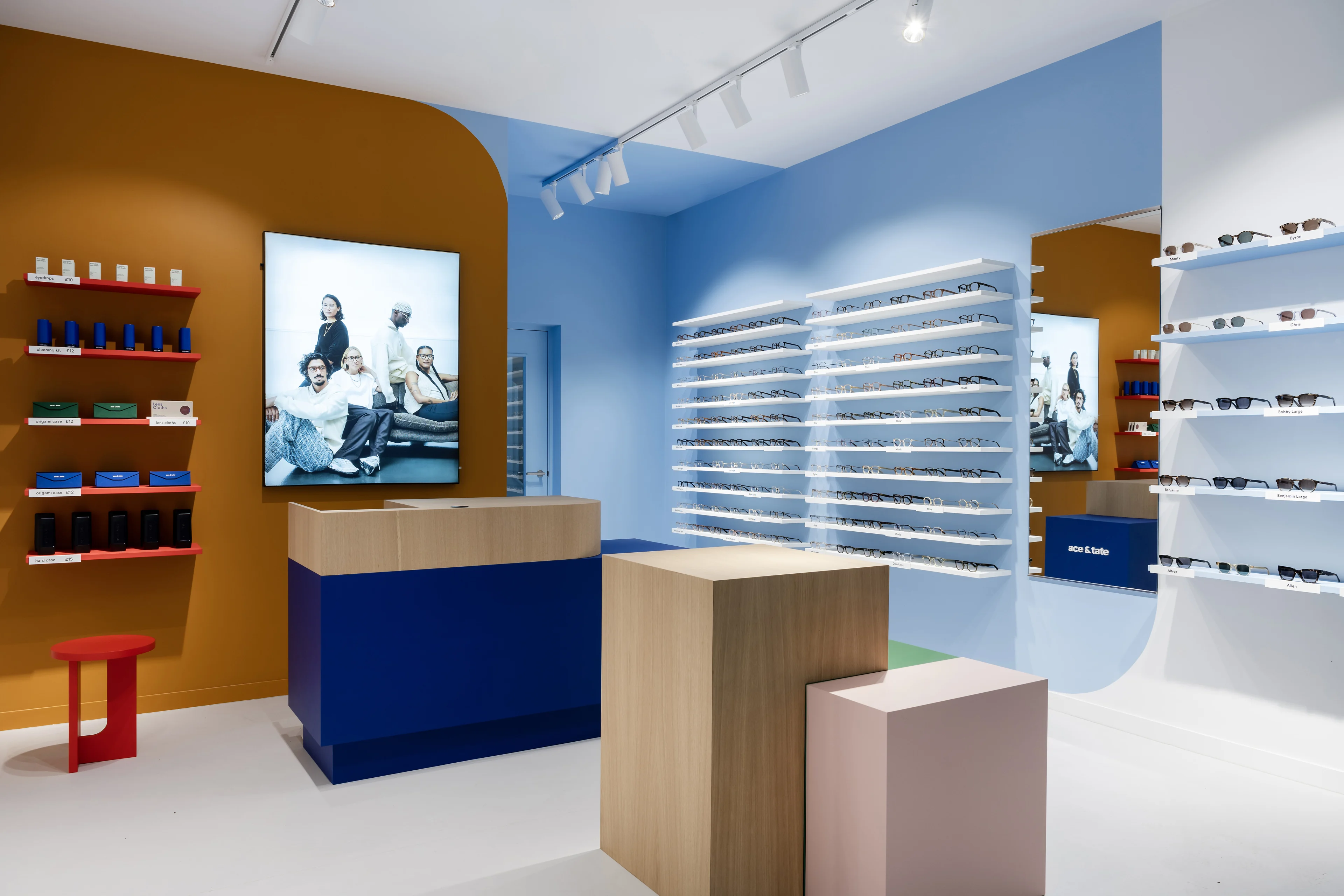 A visually striking Ace & Tate retail location with blue and white walls and illuminated wall displays of various eyeglasses and sunglasses.