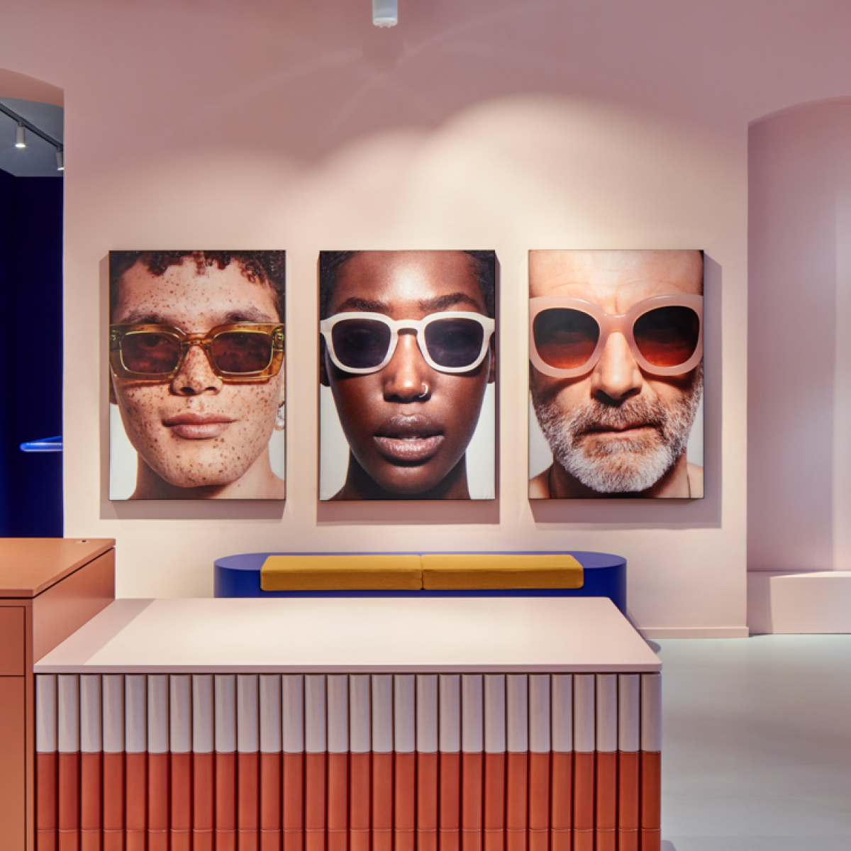 Eyewear store interior with three large portrait posters modeling sunglasses.
